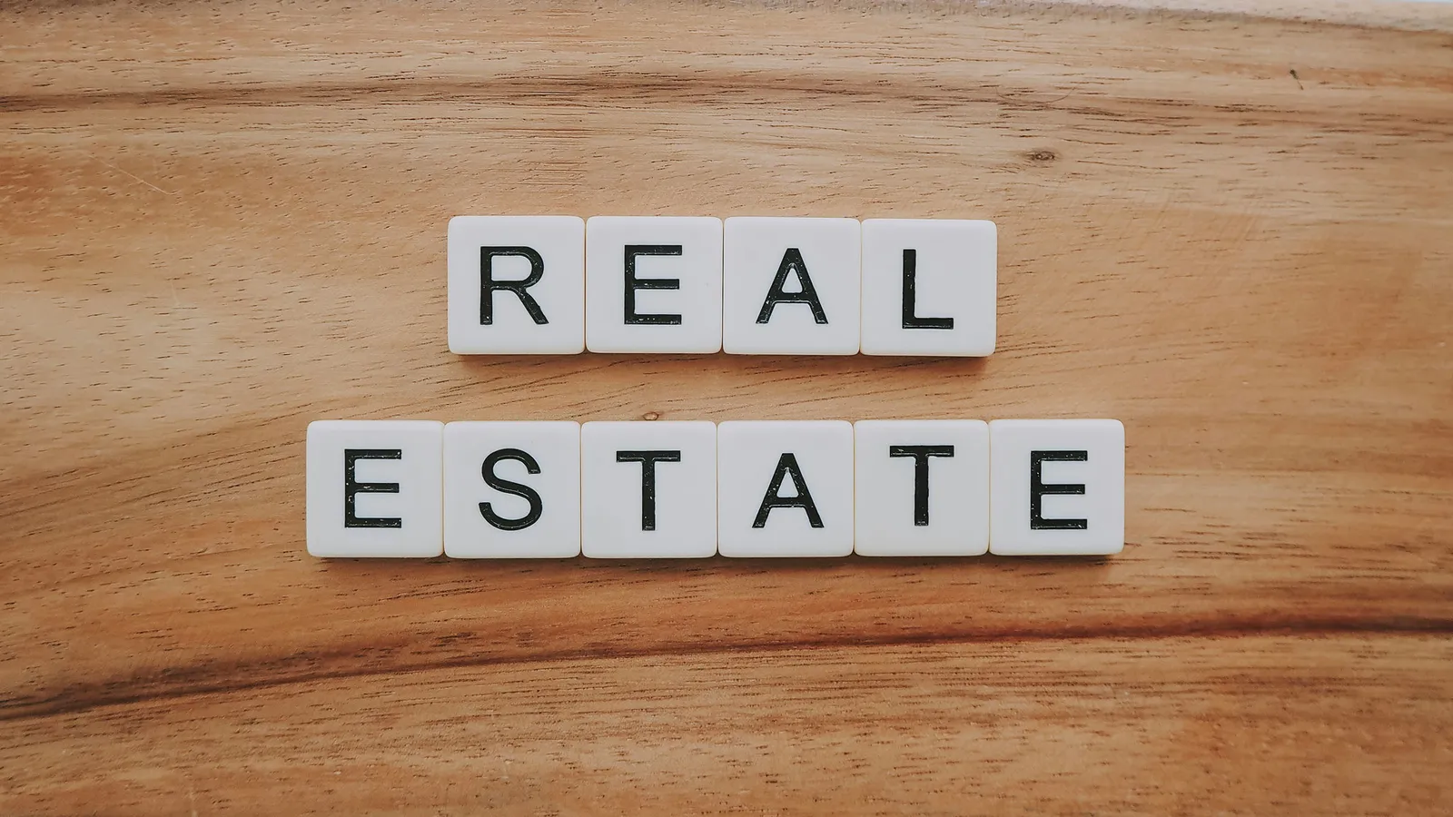 Letter tiles spelling "real estate" on a wooden table