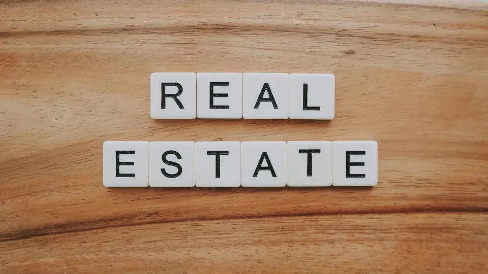Letter tiles spelling "real estate" on a wooden table
